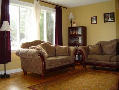 Spacious living room with gleaming hardwood and bright sunny window 