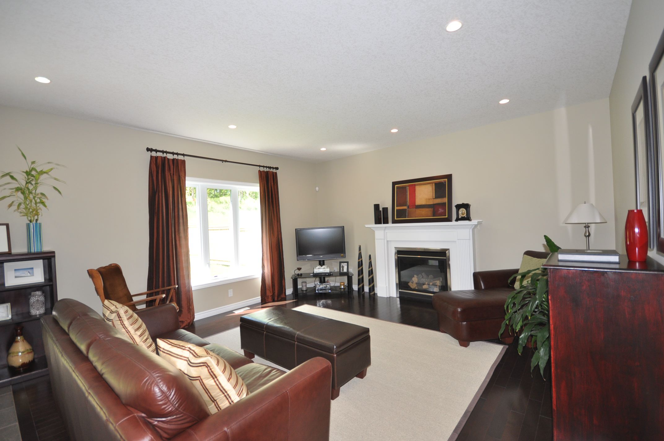 Great Room with large sunny window, cozy gas fireplace & hardwood floors
