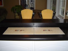 This Kitchen is updated with newer countertop ceramic inlay, painted white cupboards, ceramic flooring and an eating bar 