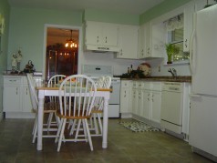 Eat in kitchen with lots of cupboards, a newer floor, counter tops, taps and ceramic backsplash. 